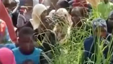 People sit on the grass in this screen grab obtained from a social media video. The faces are blurred.