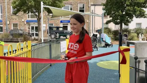 young girl in red cutting official ribbon 