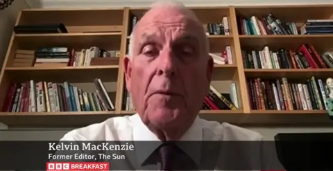 BBC Kelvin MacKenzie, who has white hair and wears a white shirt, speaks into a webcam with a bookshelf in the background.