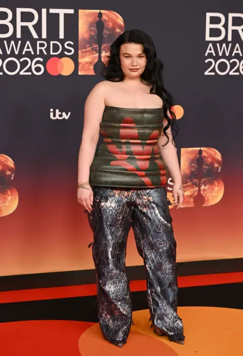 Getty Images Lola Young in a green leather peplum top and snake trousers