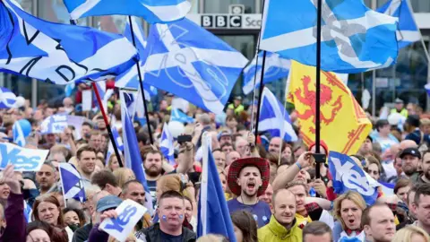 hundreds of marchers holding up Yes Scotland flags