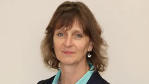 Local Democracy Reporting Service Becky Shaw, wearing a turquoise blouse and a blue jacket, stares into the camera.