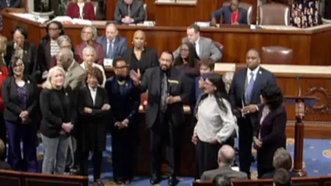 A group of Congress members stand around Al Green.