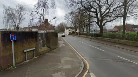 Google A Google street view image of a road going past a school with a the boundary fence and wall visible on the right. On the left is a wall with a dead end sign and a street sign which says "union street". 