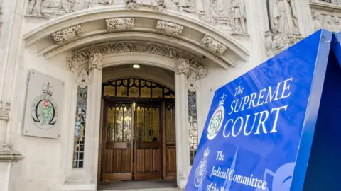 Getty Images Entrance of the Supreme Court building in London. There is a large blue sign marking the door into the court.