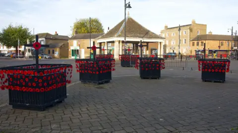 Mandy Wright Photography Red poppies on plant pots and railings displayed in town square 