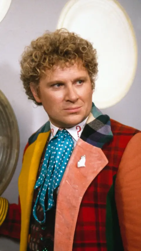 Colin Baker as Sixth Doctor in Doctor Who wearing muti-coloured coat inside the Tardis