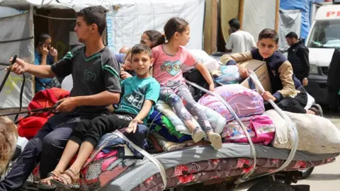 Children sit on top of belongings, as Palestinians prepare to evacuate, after Israeli forces launched a ground and air operation in the eastern part of Rafah, amid the ongoing conflict between Israel and Hamas, in Rafah, in the southern Gaza Strip, 11 May 2024