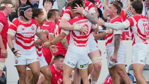 Halatoa Vailea (4th R) of Japan celebrates with teammates after scoring the team's third try