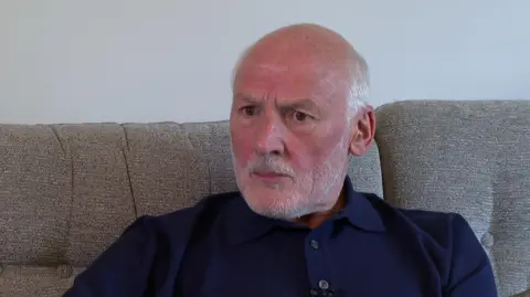 Terry Charnock, with a grey hair and beard, speaks to the BBC about his son Matthew.