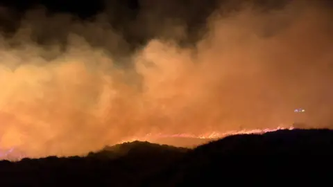 Chew Fire Station The scene of a large fire on woodland in Somerset. The orange blaze can be seen and there is smoke rising up to the sky.