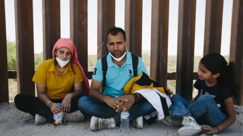 An Indian family seeking asylum in the United States rests at the border with Mexico in Yuma, Arizona, on May 20, 2022