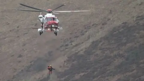 A coastguard helicopter winching a surfer to rescue in Lynmouth, Devon