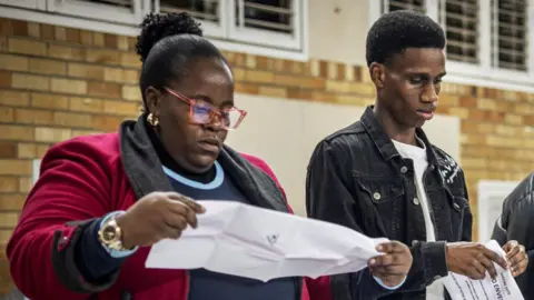 AFP A woman holding a ballot paper as Independent Electoral Commission (IEC) count ballots at the Craighall Primary School polling station in Johannesburg on May 29, 2024, during South Africa's general election. 