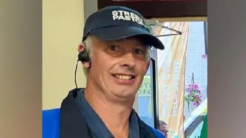 Family Photo Andrew Rogers wears a dark cap with "street pastor" written on it