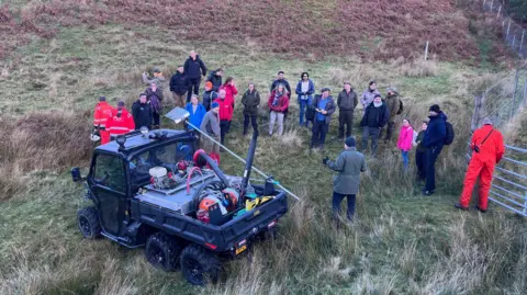 Delegates gather around an all-terrain vehicle carrying fire fighting equipment