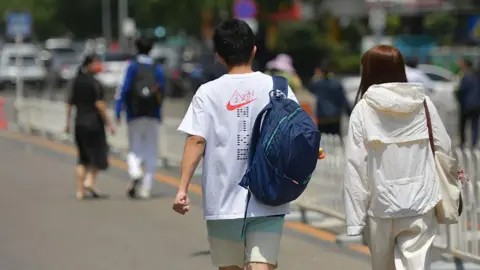 Back view of a young man and woman walking side by side on the road on a sunny day.