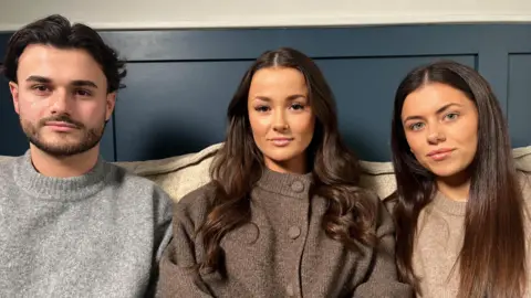 Nicola Haseler/BBC Harry Chipchase, Lulu Chipchase and Pia Chipchase sitting on a sofa looking directly at the camera. Harry has short dark hair, facial hair and is wearing a grey jumper. In the middle of the three siblings, Lulu has long dark hair which is curled and is wearing a brown cardigan which has been buttoned up. On the right, Pia Chipchase is wearing a light brown jumper and has long dark straight brunette hair.