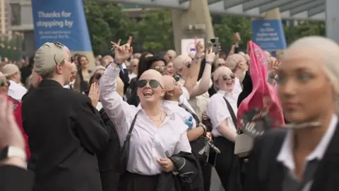 Fans dressed as Pitbull in sunglasses, bald caps and suits pictured outside the O2 Arena in London
