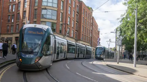 Nottingham Express Transit Two trams travel through Nottingham towards the stop in the Lace Market