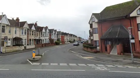 A Google Street View of a residential street of terraced houses branching off from a main road.