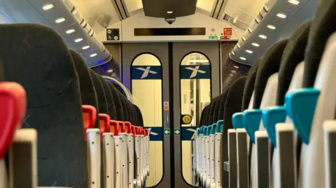 CrossCountry Rows of seats on an empty carriage on a refurbished CrossCountry voyager train. The image shows seats on either side of the photo, with red arm rest levers on the right and blue ones on the left.