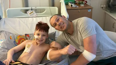 Sophie Hodgson-Smith Jasper's father Matt (right) and Jasper(left) smiling at the camera during transplant. 