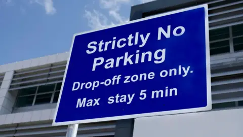 An airport sign saying "drop off only" on white letters on a blue background