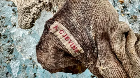 Jimmy Chin A sock embroidered with "A.C. Irvine", on  with a boot, has been discovered connected  the Central Rongbuk Glacier beneath  the North Face of Mount Everest by a squad  led by Jimmy Chin.