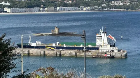 MV Arrow berthed alongside the Victoria Pier in Douglas with the Tower of Refuge in the background.