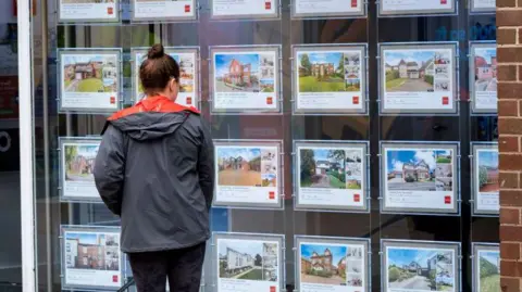 Young woman looking in an estate agent window