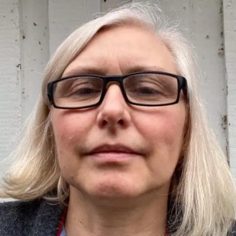 Janis Armstrong Janis Armstrong has fair, shoulder-length hair and is wearing glasses.