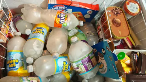 John Turbefield The inside of a freezer stocked with several large bottles of water and other frozen goods 