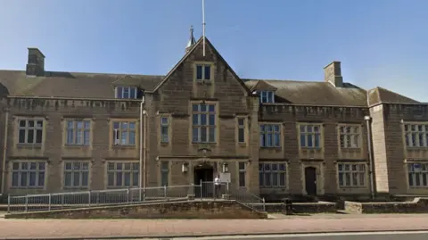 Carlisle Magistrates' Court - a Victorian Sandstone building, two storeys high with an additional floor in the roof space. It has several mullioned windows and a ramp leads from the street to the entrance.