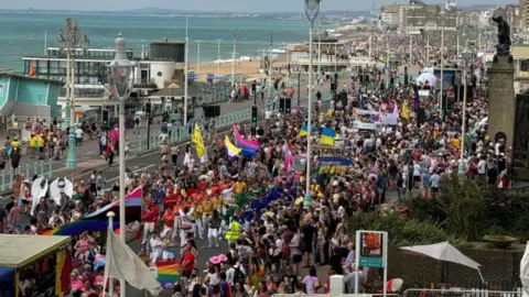 BBC/Anthony Martin Thousands of people walking from Hove to Brighton along the seafront road. To the left is the sea and beach