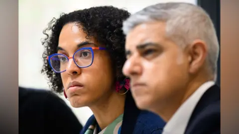 Getty Images A woman with glasses and short curly black hair sits next to London mayor Sir Sadiq Khan.