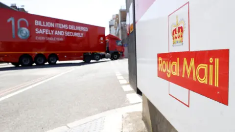 A white sign with a Royal Mail logo sits in the foreground. Behind it is a red Royal Mail delivery truck.