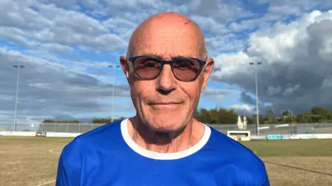 Chris Burley - a man with a bald head wearing sunglasses and a blue running top