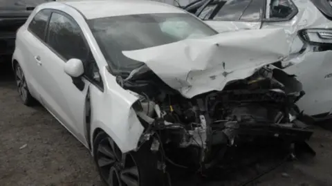 Sussex Police a crumpled white Kia Rio car with extensive damage to the bonnet and bumper