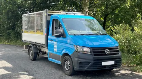 Torridge District Council Council A blue street cleansing van. It has a large cage on the back for securing waste and other items 