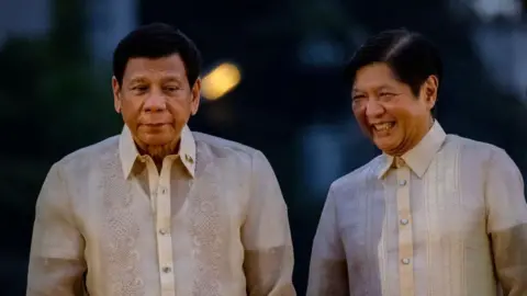 Getty Images Rodrigo Duterte and Ferdinand Marcos Jr standing side-by-side in white button-up shirts