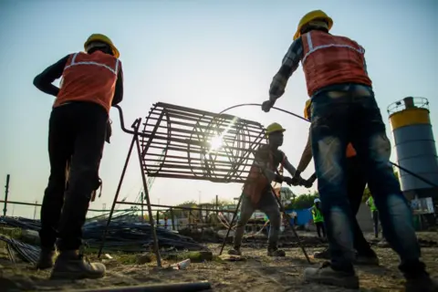 Getty Images Los trabajadores construyen los cimientos en el sitio de construcción de la nueva fábrica de Dixon Technologies Ltd., en Noida, India, el viernes 22 de marzo de 2024. Dixon Technologies Ltd., un fabricante por contrato indio, se está beneficiando de un auge en nuevos negocios de clientes como el fabricante chino de teléfonos inteligentes Xiaomi Corp. y Samsung Electronics Co. de Corea del Sur que desean utilizar sus fábricas para fabricar bienes para la creciente clase media de la India.