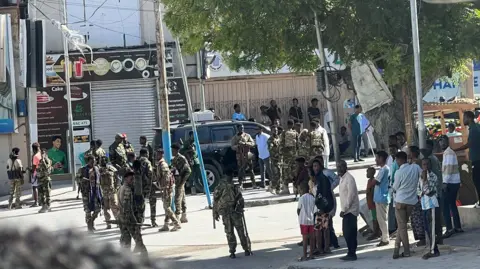Reuters Members of Somali government forces in camouflage uniform stand among civilians at a street junction in Mogadishu