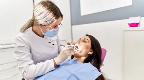 Getty Images A pistillate   lying connected  a dentists' seat  with her rima  unfastened  - a dentist is examining her teeth