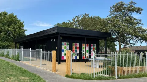 Cherry Tree Youth Club's new hub is a black timber clad, single storey building, with art on the external walls and fenced in gardens.