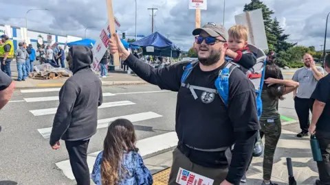 Ryan Roberson asistió a la protesta con su hija frente a él, de espaldas a la cámara, y su hijo pequeño en un portabebés en su espalda.