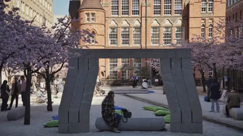 A woman sat on a concrete sculpture in the heart of a square with a row of cherry blossom trees to the left and right