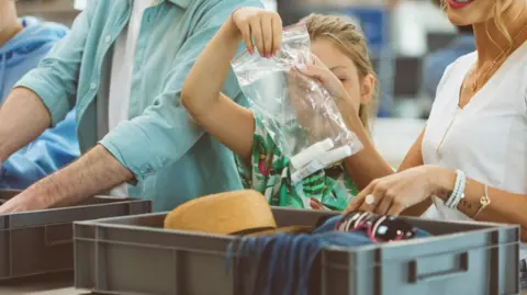 A girl holding a plastic bag with bottles of liquid at airport security