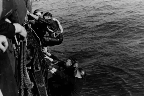 Picture Post/Hulton Archive/Getty Images Men clamber aboard a ship from the water. They are soaking wet. The image is black and white