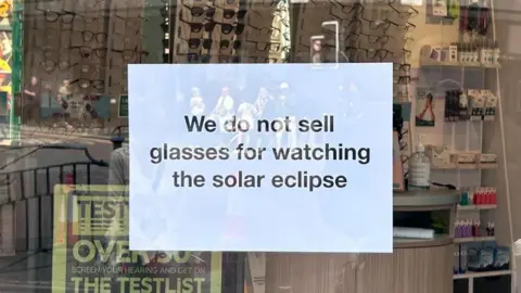 A sign in a shop window which reads: "We do not sell glasses for watching the solar eclipse".